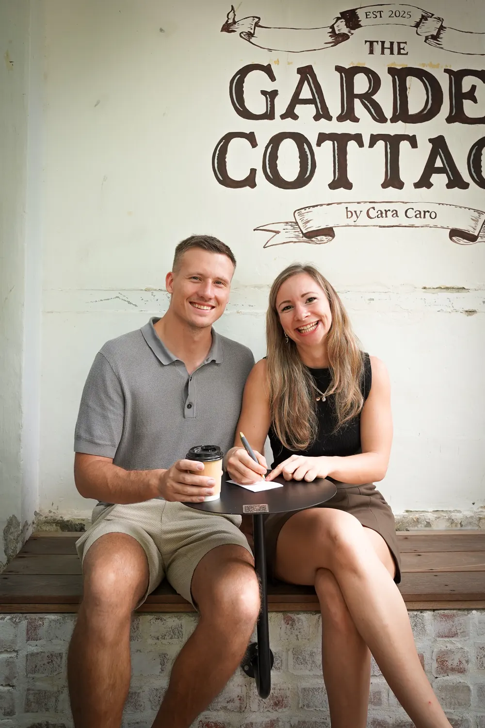Sophie und Tobias sitzen mit Kaffee und Notizzettel vor einem Café