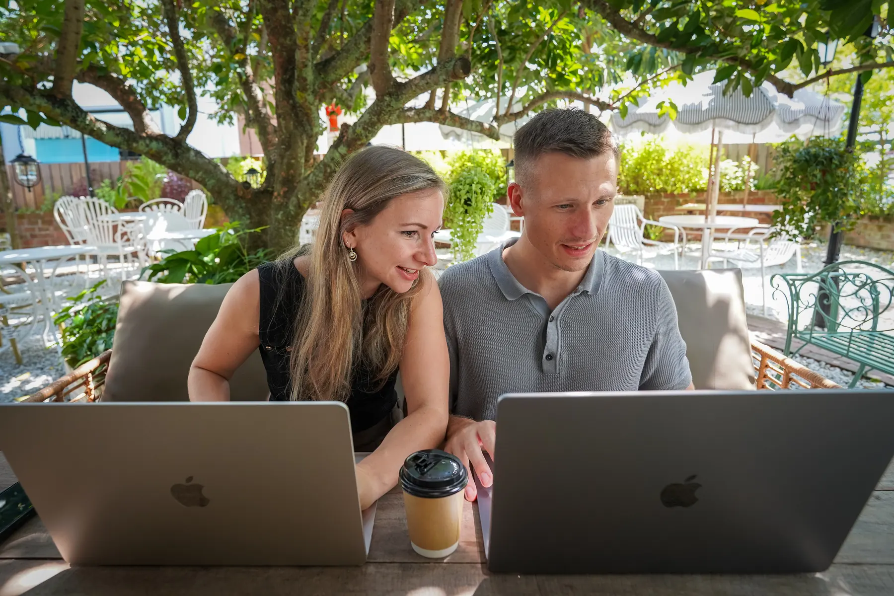 Sophie und Tobias arbeiten gemeinsam am Laptop in einem Café